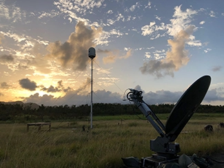 Radar dish by a small radar antenna in a field
